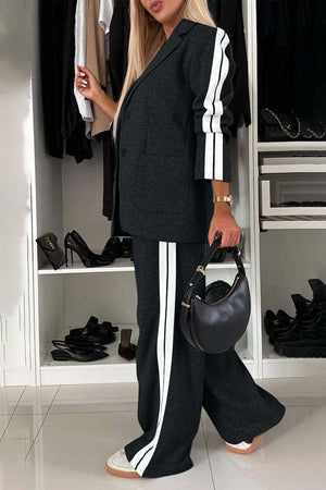 Woman wearing a full size contrast lapel collar top and pants set, styled with a black handbag.