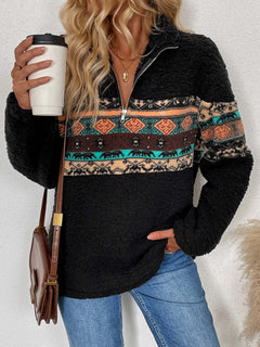 Stylish woman in quarter zip geometric long sleeve sweatshirt, holding coffee cup and showcasing vibrant pattern.