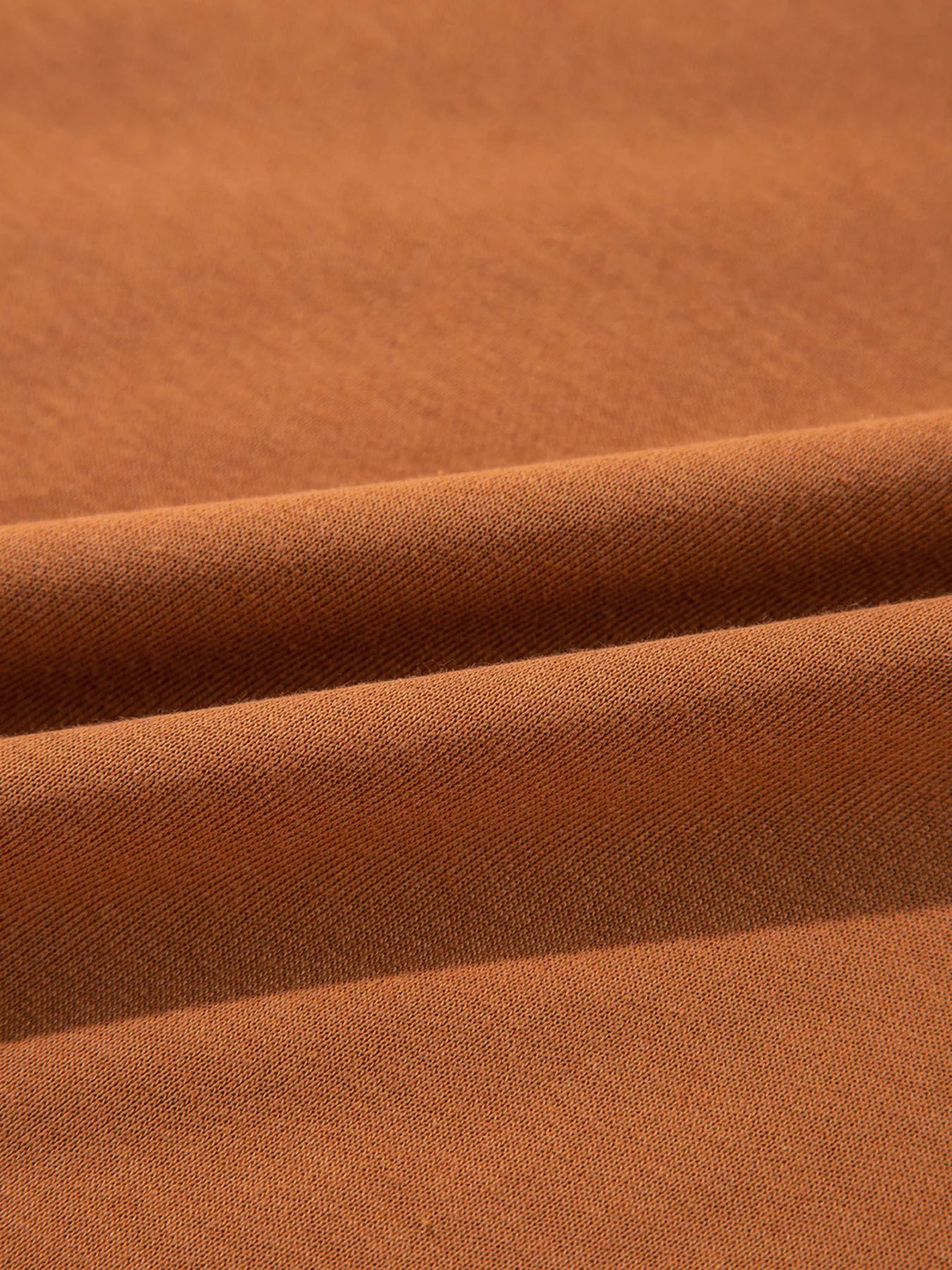 Close-up of soft brown fabric showcasing textures and folds, ideal for comfortable clothing.
