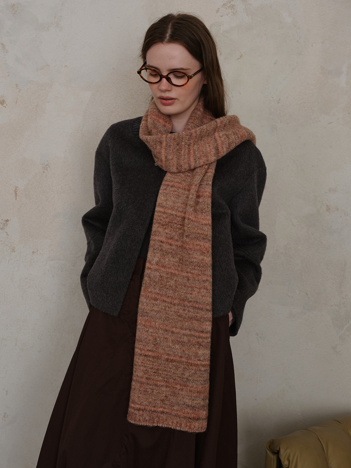 Woman wearing a striped detail knit scarf made from fur, styled with a cozy cardigan and a long dress.