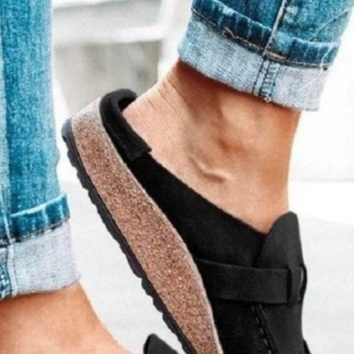 Close-up of a stylish round toe low heel buckle loafer worn with rolled cuff jeans.