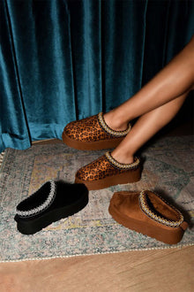 WILD DIVA platform clogs in black, brown, and leopard print with embroidered trim on a stylish rug.