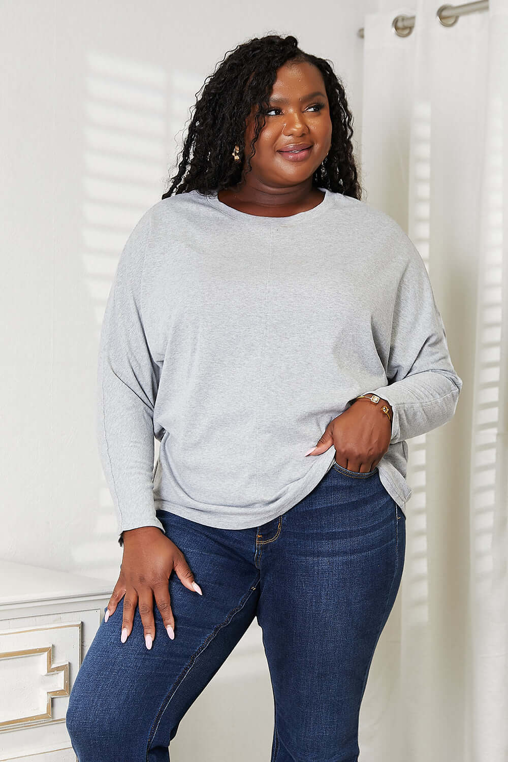 Double Take Seam Detail Round Neck Long Sleeve Top modeled by a woman, showcasing its relaxed fit and elegant style.