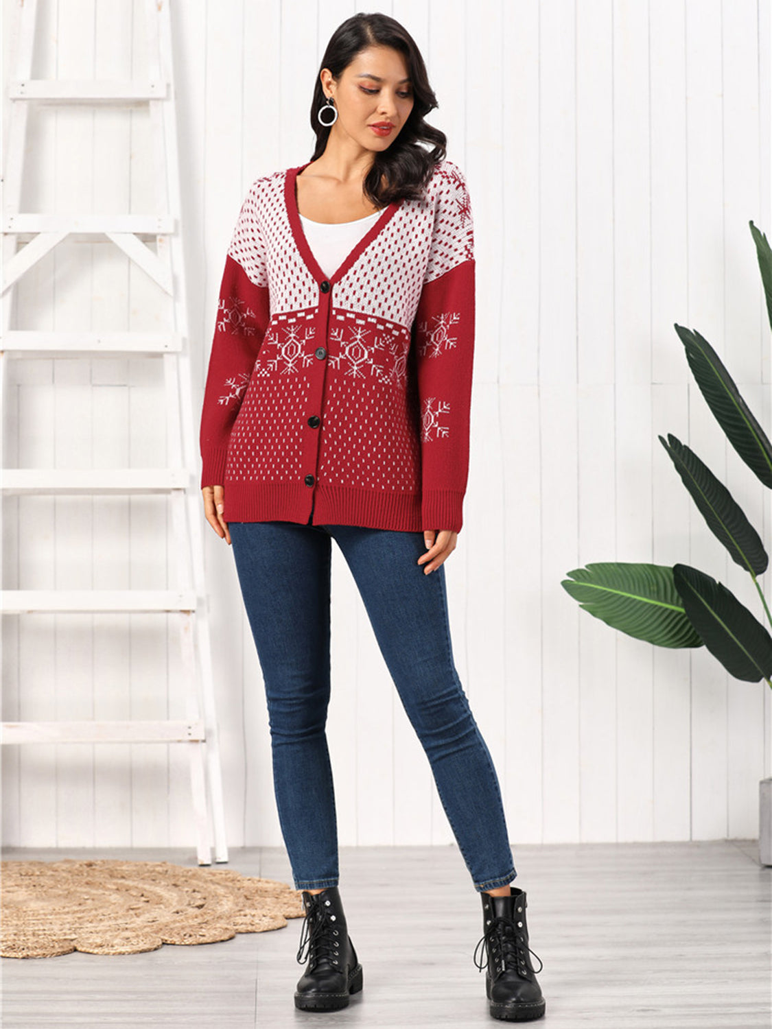 Model wearing a Snowflake Button Down Cardigan in red with white snowflake patterns, styled with blue jeans.
