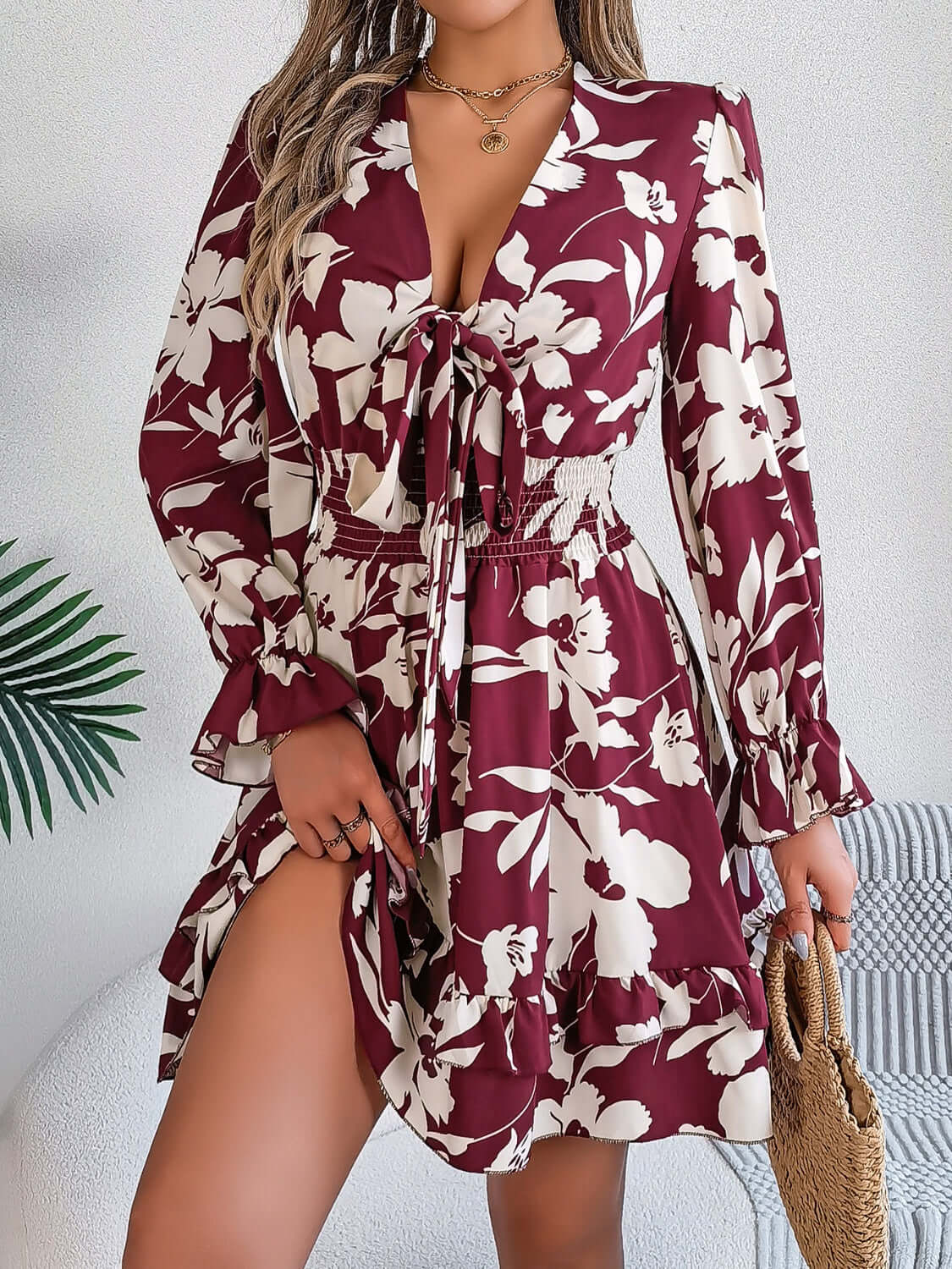 Tied ruffled printed long sleeve dress in burgundy with floral design, featuring a cinched waist and flared sleeves.