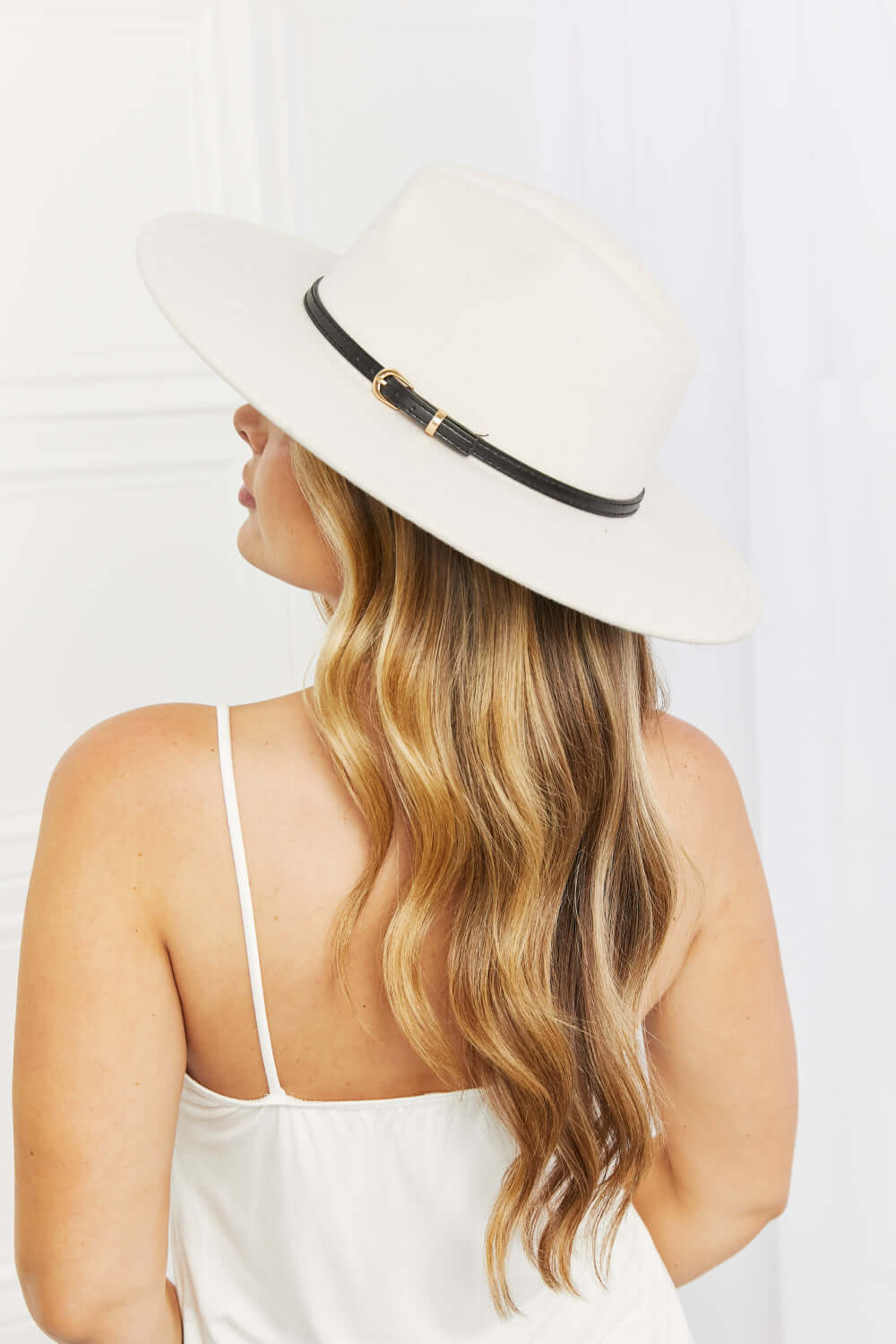 Woman wearing the Fame Keep It Classy Fedora Hat with a beige color and stylish black belt buckle.