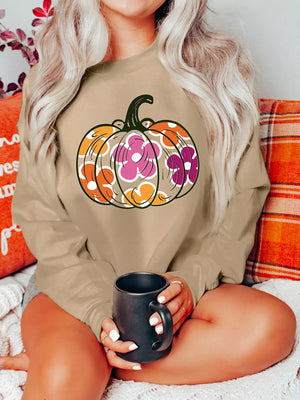 Woman wearing a Halloween floral pumpkin sweatshirt, holding a black mug, sitting on a cozy couch.