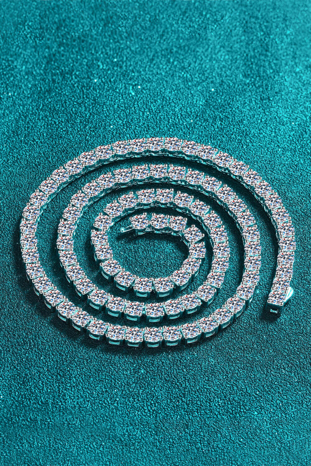 Elegant moissanite rhodium-plated necklace, minimalist design, displayed in a spiral on textured background.