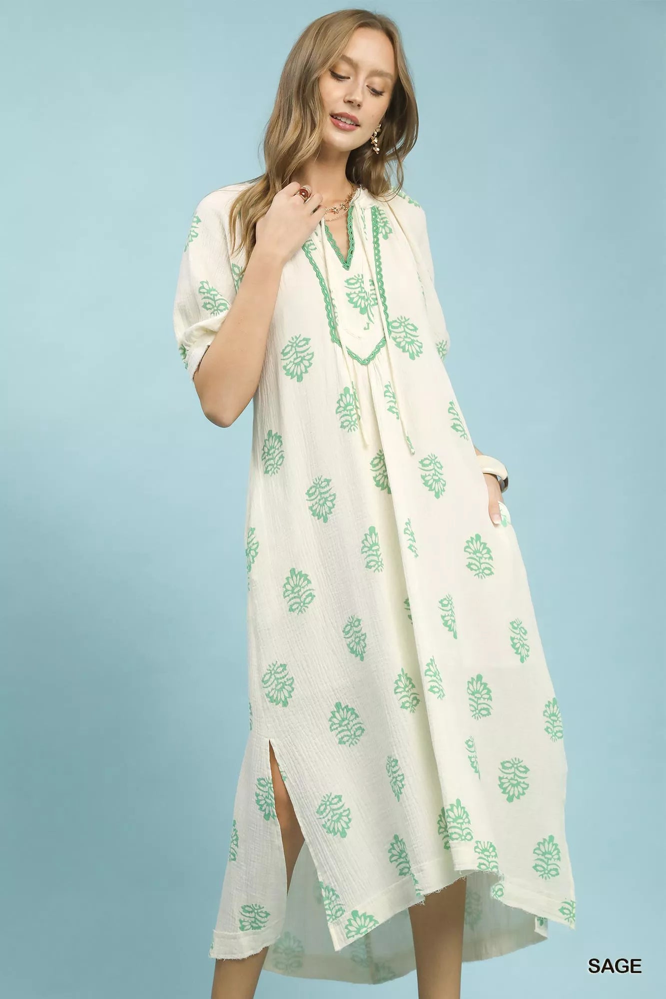 Umgee Printed Cotton Gauze Midi Dress showcasing a split neckline with tassel ties and side slits for movement, in a breezy sage design.