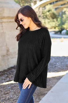 Fashionable woman in a black ribbed knit top, enjoying a sunny day outdoors with a casual, stylish look.