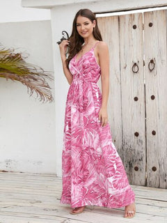 Model in a pink printed surplice spaghetti strap dress, showcasing floral patterns against a rustic background.