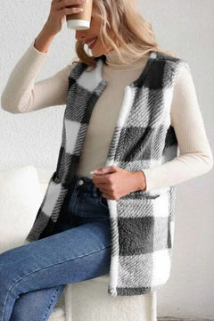 Woman wearing a Sherpa plaid open front vest coat over a cream turtleneck, holding a coffee cup.