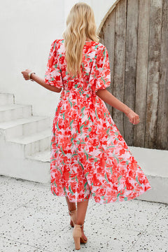 Back view of a model in a smocked printed V-neck short sleeve dress with floral design.