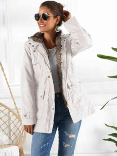 Woman wearing a full size hooded jacket with detachable liner, stylishly paired with sunglasses and casual jeans.