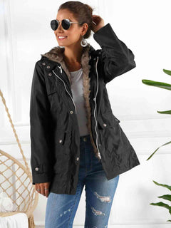 Woman wearing a black full-size hooded jacket with detachable liner and sunglasses, styled with ripped jeans.