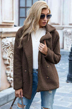 Woman wearing a brown lapel collar sherpa coat over a white top, styled casually with sunglasses.