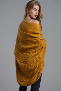 Stylish model wearing a mustard yellow open front ribbed longline cardigan from the back in a studio setting.