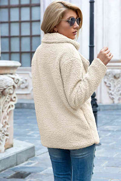 Woman wearing a stylish cream lapel collar sherpa coat, paired with sunglasses, in a casual urban setting.