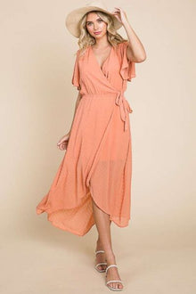 Chic Swiss Dot Dress in soft peach color, featuring ruffled sleeves and a flattering wrap design for elegant style.