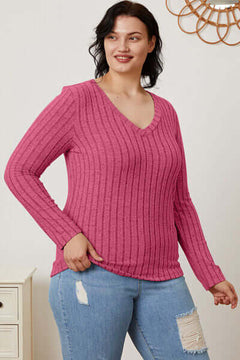 Model wearing a pink ribbed V-neck long sleeve t-shirt paired with light-wash jeans, showcasing a casual style.