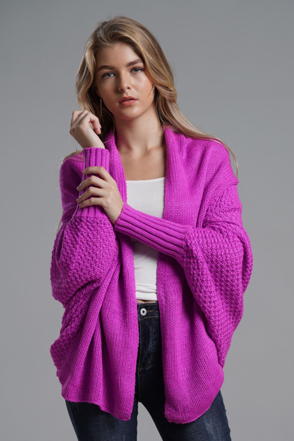 Model wearing a pink dolman sleeve open front cardigan with ribbed trim, styled casually in a studio setting.