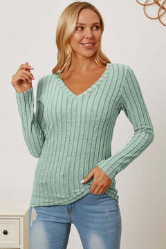 Woman in a light green ribbed V-neck long sleeve T-shirt paired with jeans, showcasing a stylish and comfortable look.