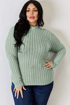 Model wearing a green ribbed mock neck long sleeve t-shirt, paired with blue jeans, showcasing a stylish casual look.