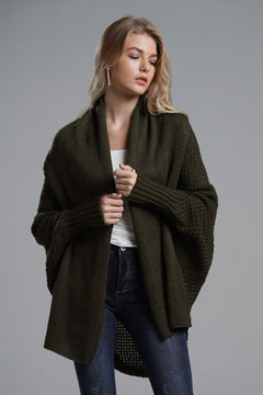 Model wearing a longline olive green dolman sleeve cardigan, styled casually with a white top and jeans.