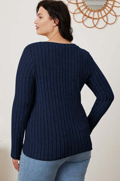Back view of a plus size woman wearing a navy ribbed long sleeve sweater with a relaxed fit.
