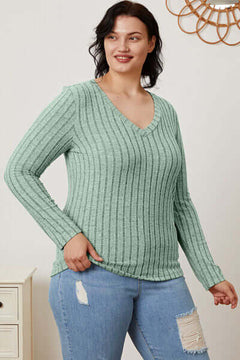 Model wearing a mint green ribbed V-neck long sleeve t-shirt paired with distressed jeans.