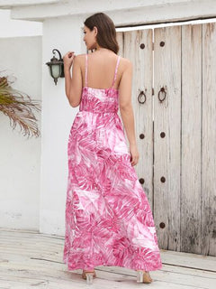 Woman wearing a pink printed surplice spaghetti strap dress with a floral design, standing on a wooden deck.