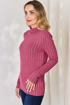 Model wearing a pink ribbed mock neck long sleeve t-shirt, showcasing its stylish design and fitted silhouette.