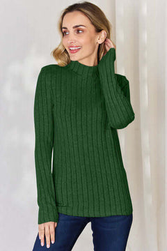 Woman wearing a green ribbed mock neck long sleeve t-shirt, smiling with a relaxed pose.