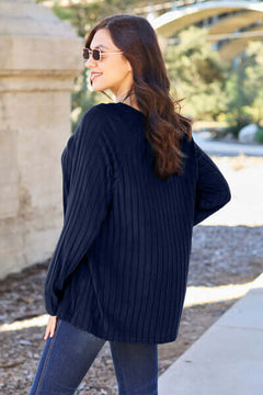 Woman wearing a navy ribbed long sleeve knit top outdoors, showcasing a relaxed fit and stylish sunglasses.