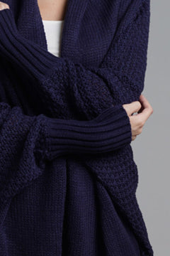 Close-up of a woman wearing a navy blue longline cardigan with ribbed sleeves and an open front.