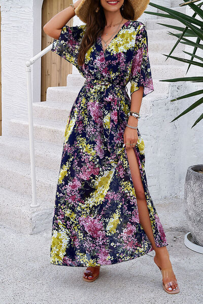 Model wearing a vibrant printed tied half sleeve dress with a side slit and floral design, perfect for summer outings.