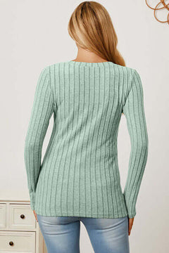 Back view of a woman wearing a mint green ribbed long sleeve t-shirt paired with light blue jeans.